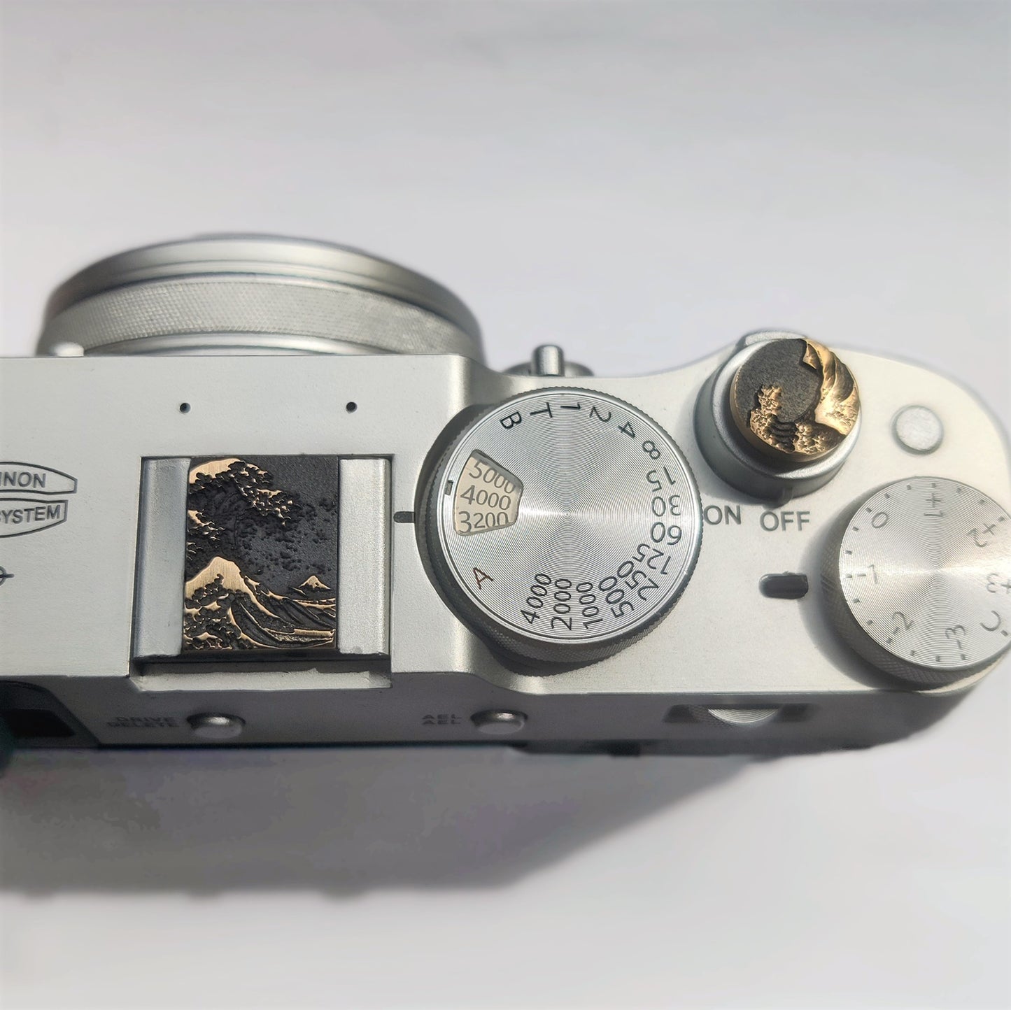 Gold ocean wave camera hot shoe cover mounted and shutter button on Fujifilm X100