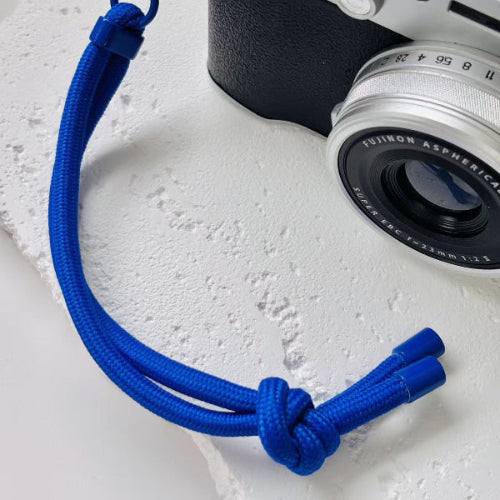 Camera with blue strap on a light gray surface