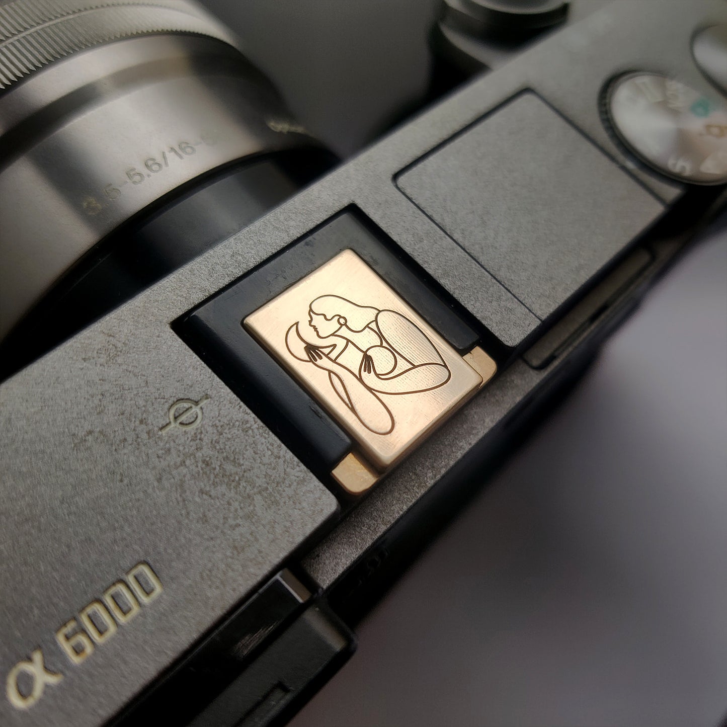 gold hot shoe cover engraved with Maggie Stephenson art on Sony camera