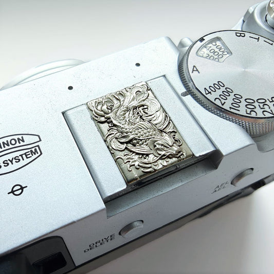 Close-up of a vintage camera with an arowana embossed design hot shoe cover.