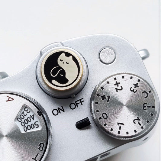Close-up of a camera shutter button with dog and cat design on the surface