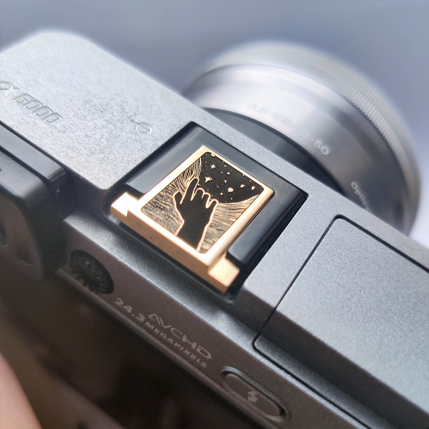 Side angle of gold hot shoe cover with artistic space-themed engraving