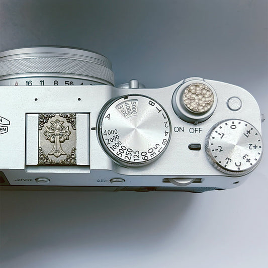 Close-up of a silver camera body with dials and branding on a gray background