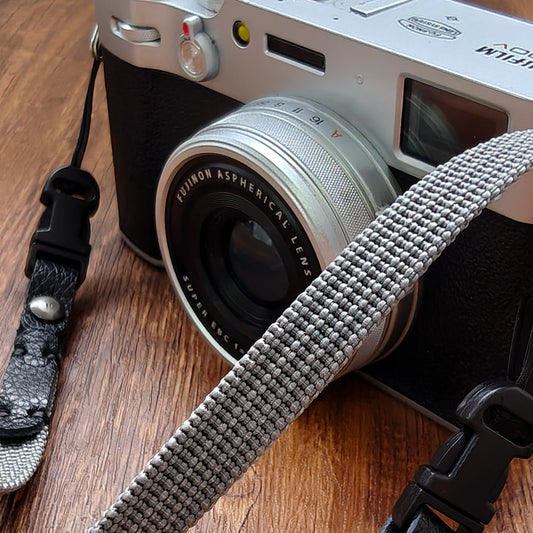 Close-up of gray canvas camera strap showing slim profile and leather connector detail