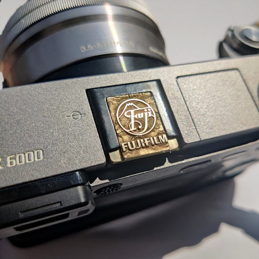 Textured gold brass camera hot shoe cover with mountain-inspired design