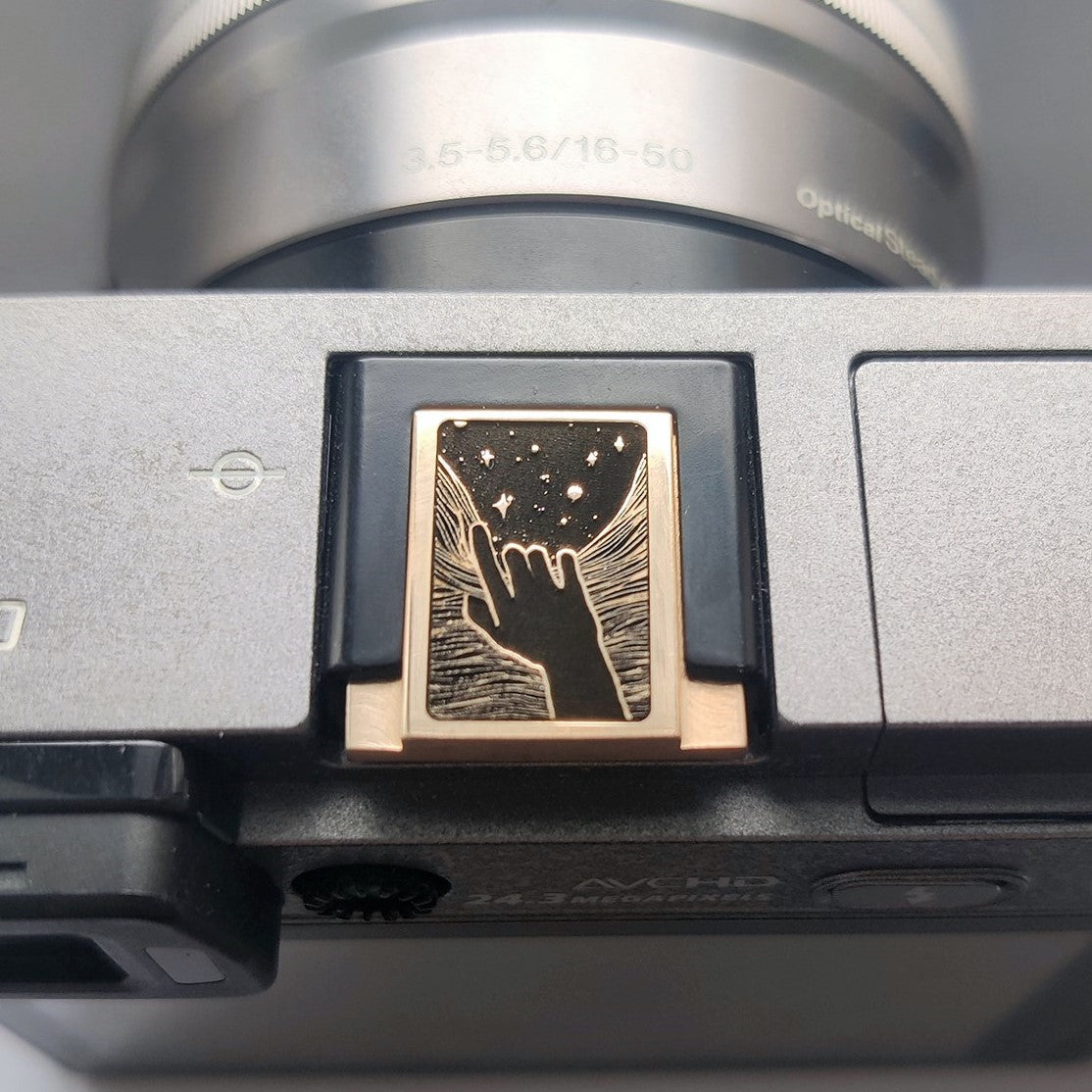Gold brass hot shoe cover with engraved hand and stars design on Fujifilm X100