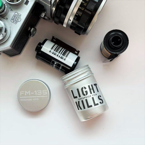 Film canisters and camera equipment on a white surface with 'Light Kills' text.