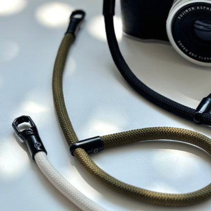 Camera with a brown rope strap on a light surface