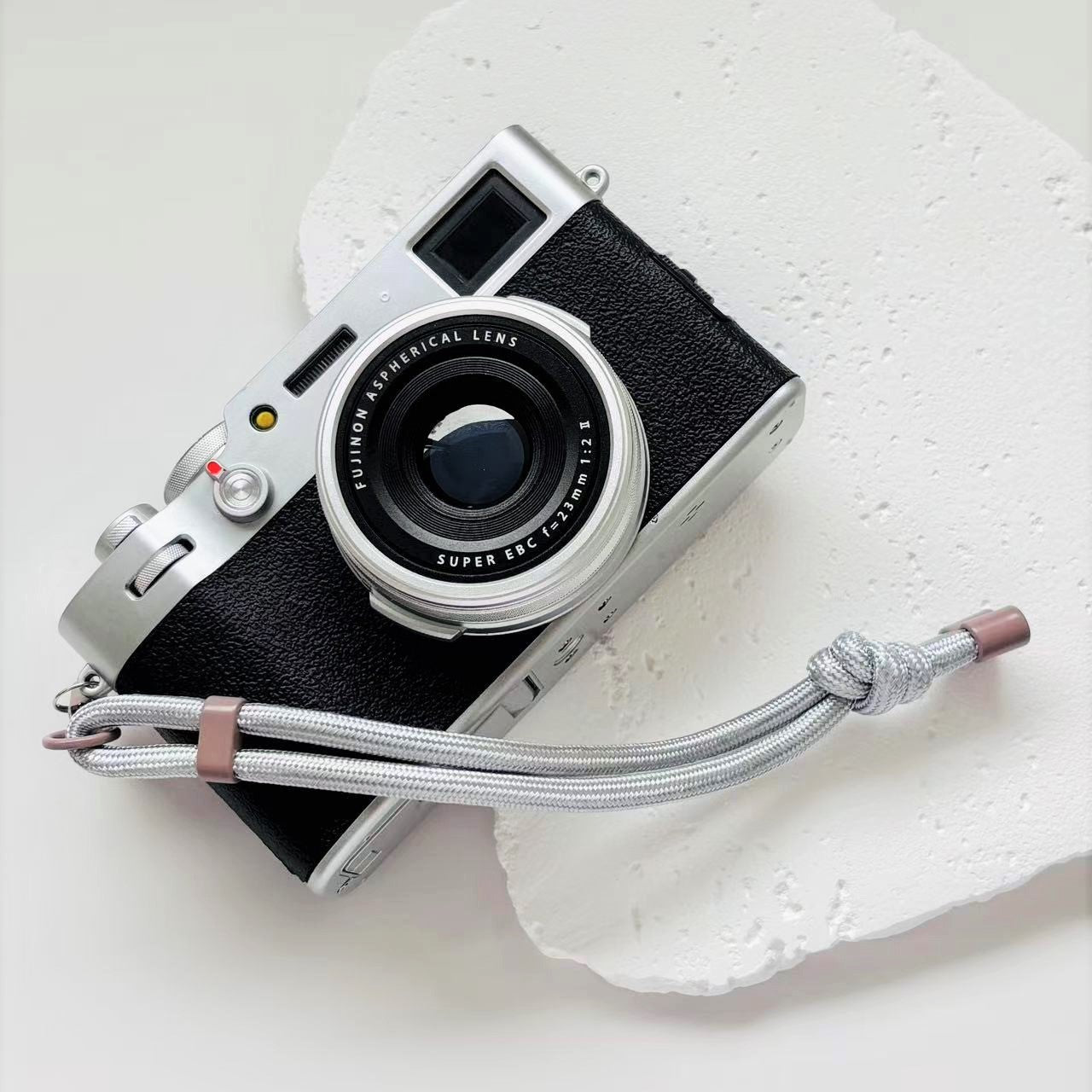 Vintage camera with a strap on a textured white surface