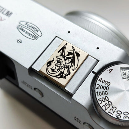 Charizard gold brass hot shoe cover on Fujifilm camera - front view