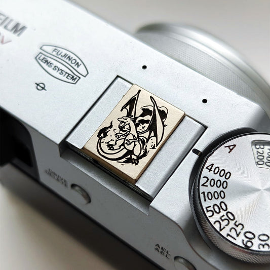 Charizard gold brass hot shoe cover on Fujifilm camera - front view