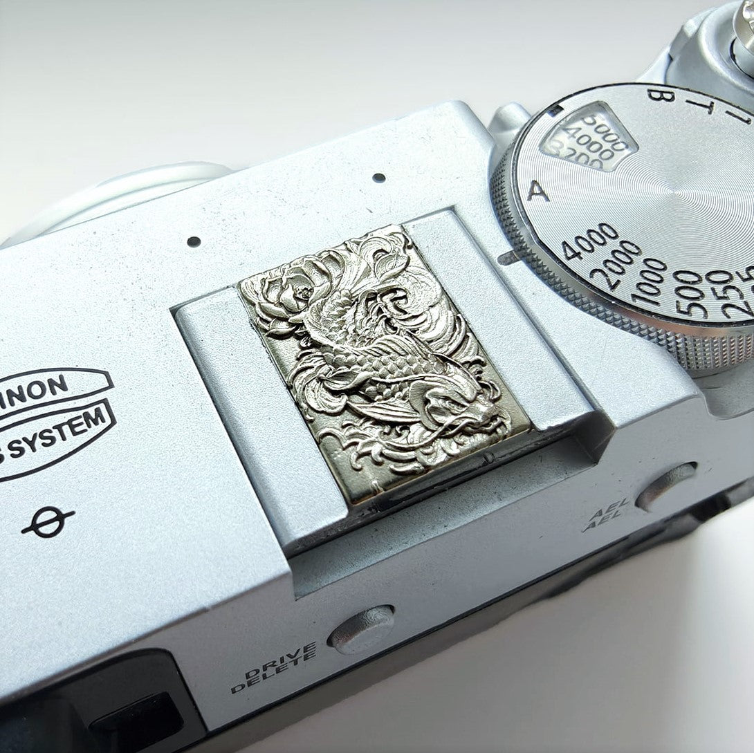 Close-up of a vintage camera with an arowana embossed design hot shoe cover.
