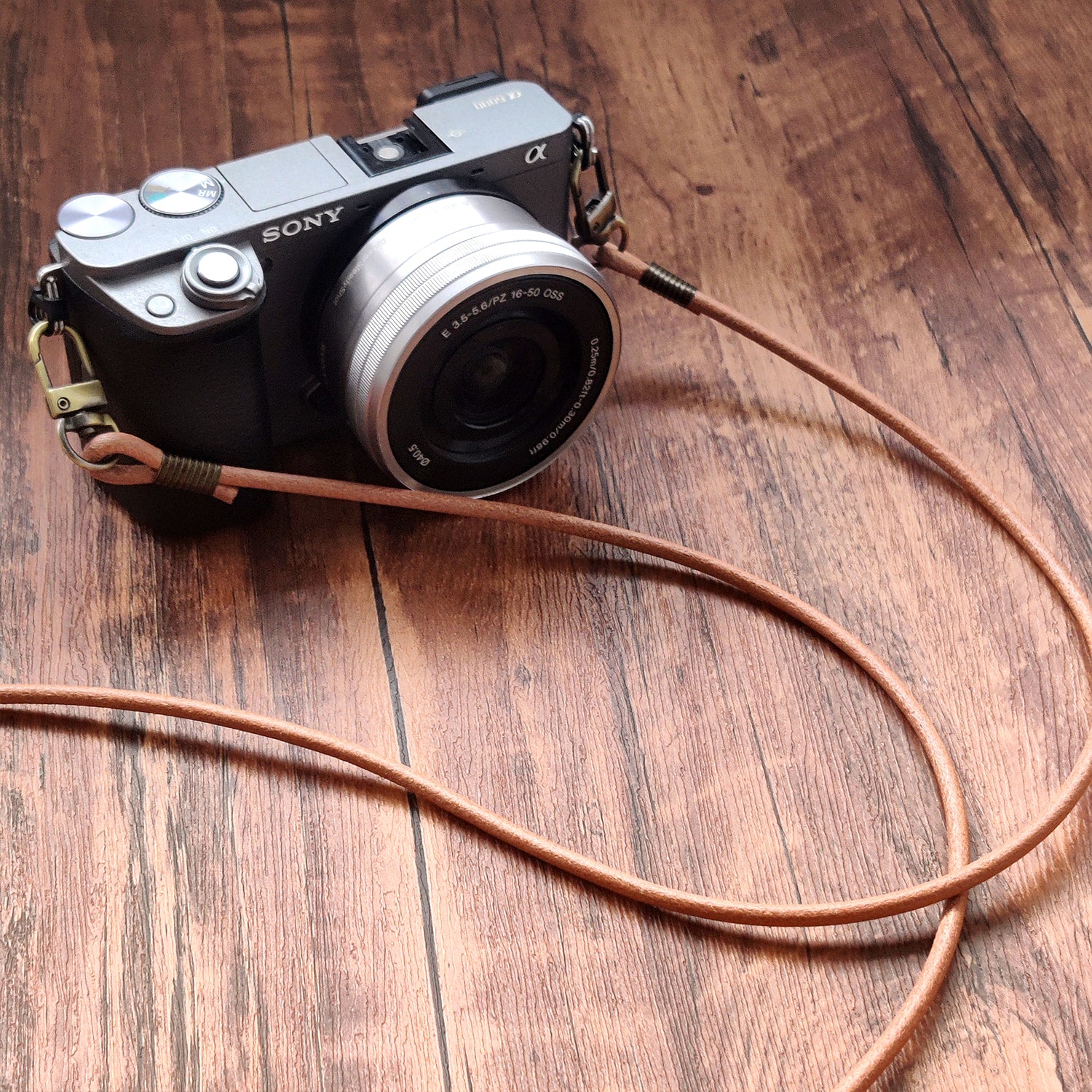 Sony camera with a leather strap on a wooden surface