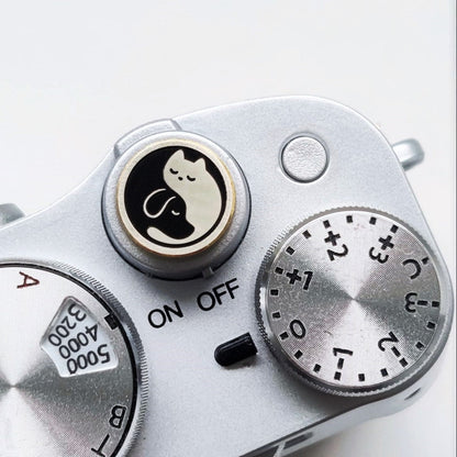 Close-up of a camera shutter button with dog and cat design on the surface