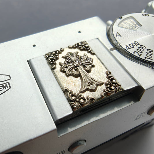 Close-up of a watch with an ornate cross emblem on a metallic background