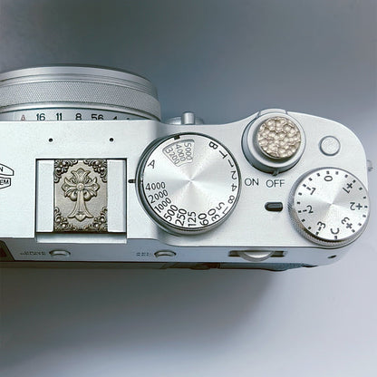 Close-up of a silver camera body with dials and branding on a gray background