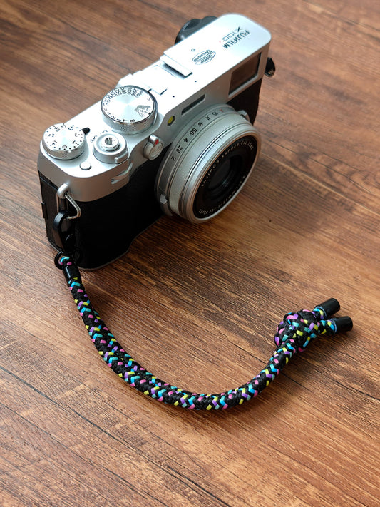 Camera with a colorful strap on a wooden surface