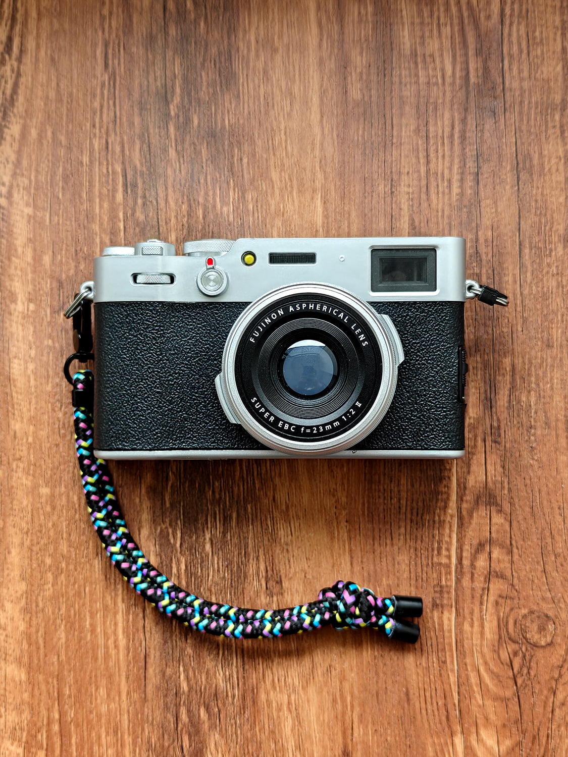 Camera with a colorful strap on a wooden surface