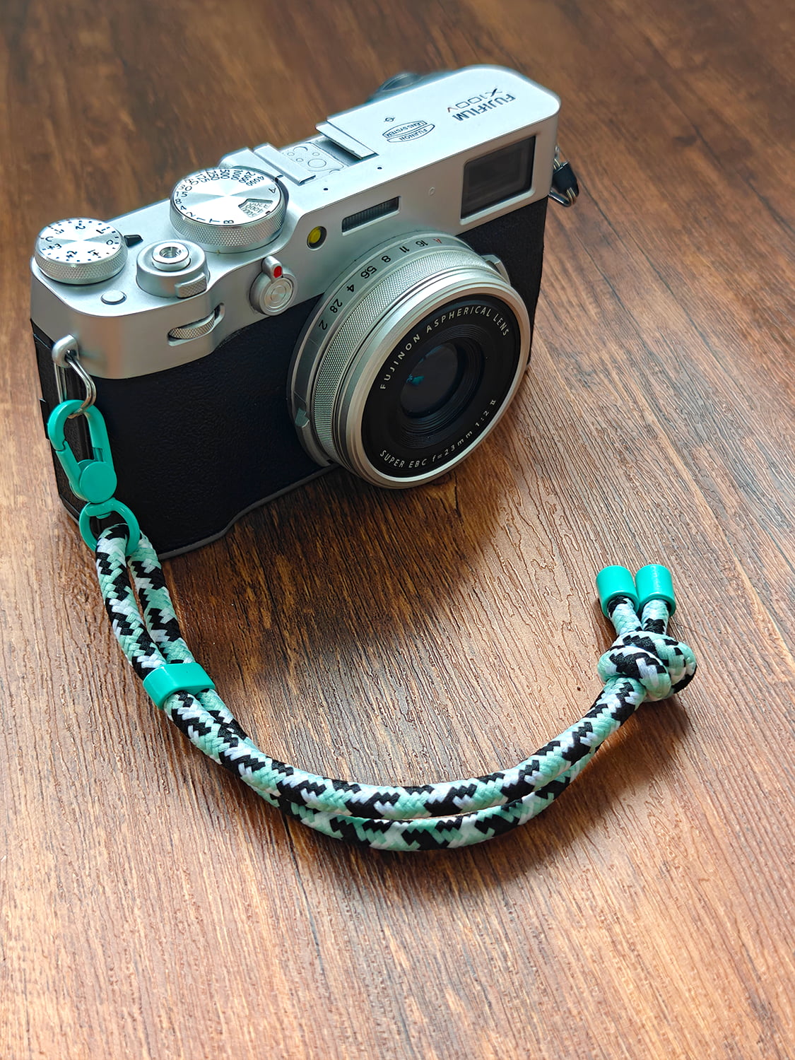 Camera with a camouflage strap on a wooden surface