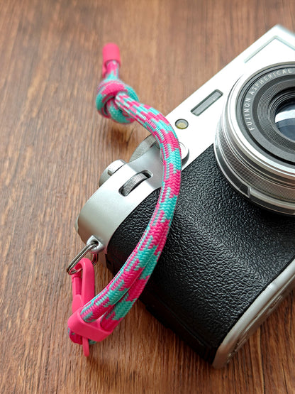 Camera with a colorful strap on a wooden surface