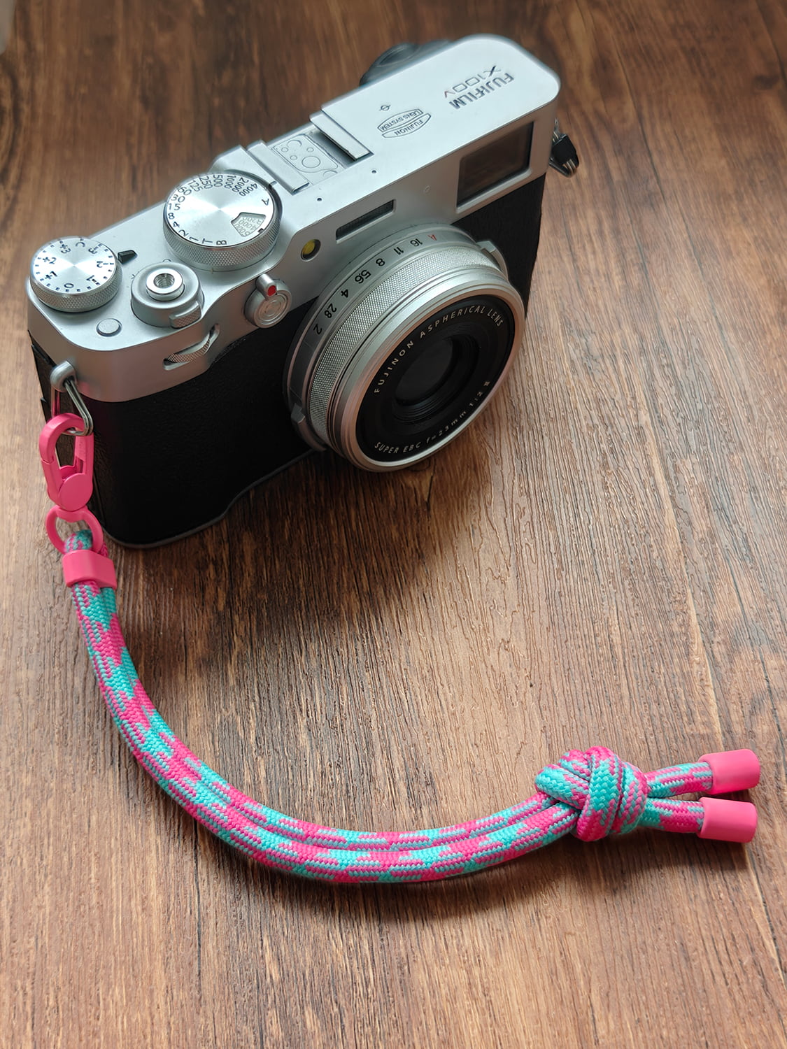 Camera with a colorful strap on a wooden surface