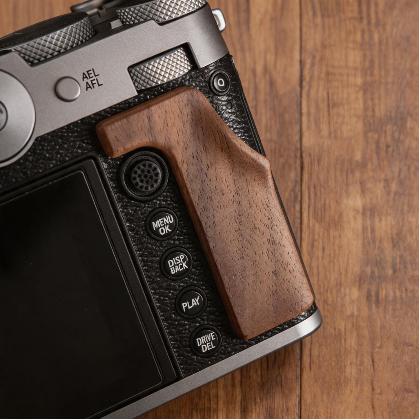 A close-up of a Fuji GFX100RF camera grip set against a wooden tabletop background.