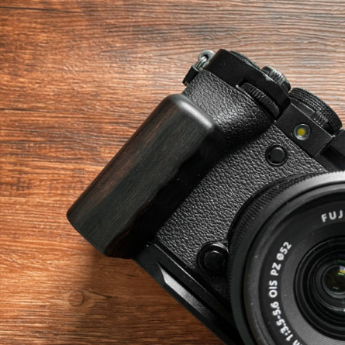 Fujifilm XT5 camera with a black wood L-shaped grip on a wooden surface