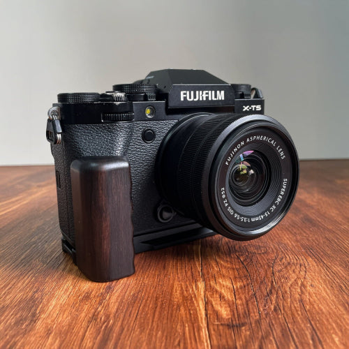 Fujifilm camera with a dark ebony wood L-shaped grip on a wooden surface
