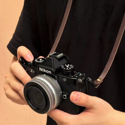 Person holding a Nikon camera with a grain leather strap