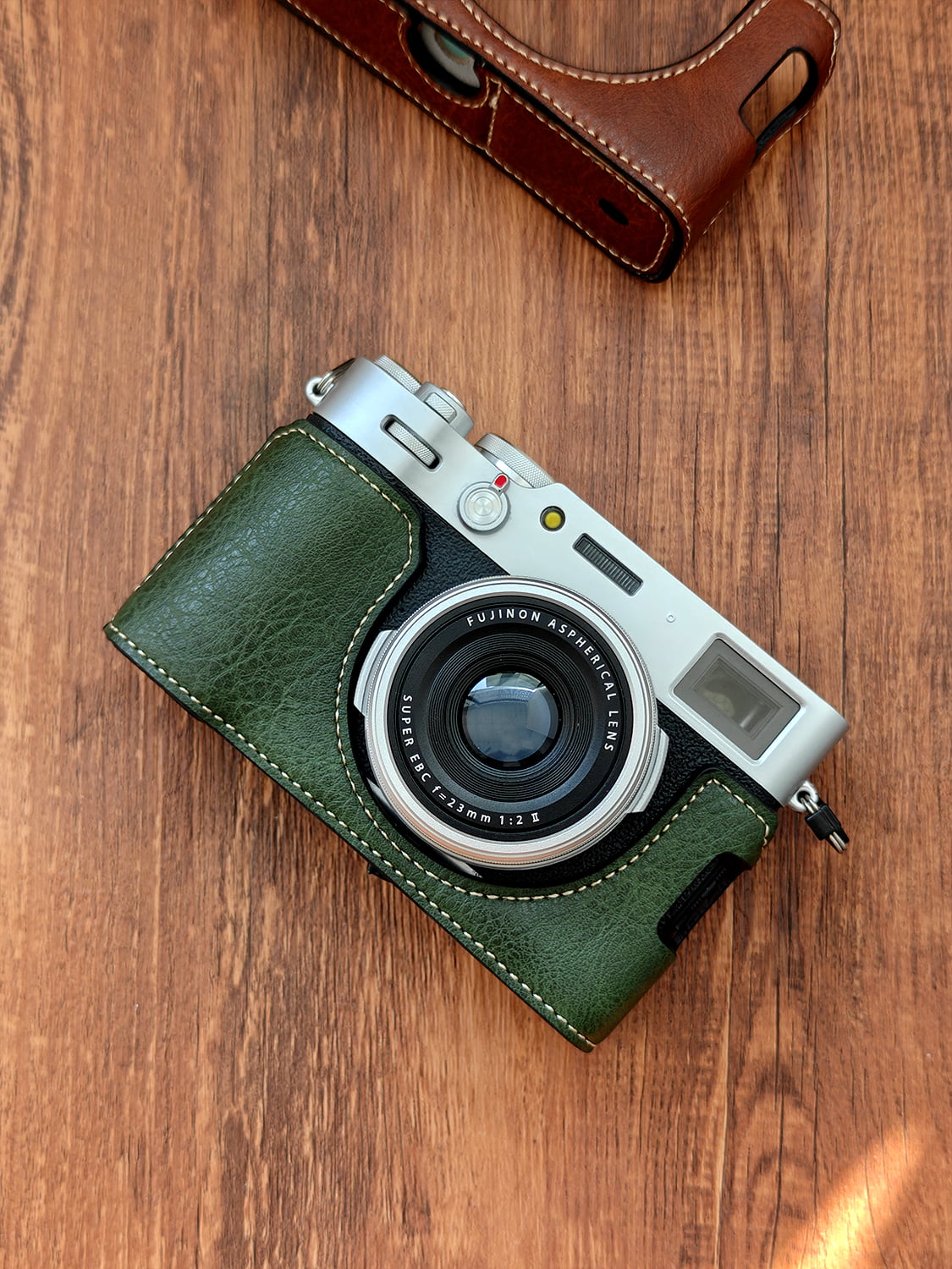 Fujifilm X100vi camera with green leather case on a wooden surface