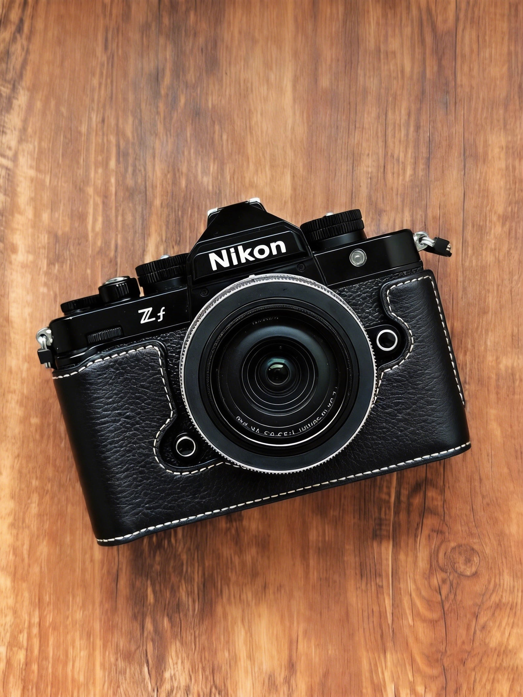 A Nikon Zf mirrorless camera with a black leather camera cover and front lens protector, photographed from above on a brown wooden surface.