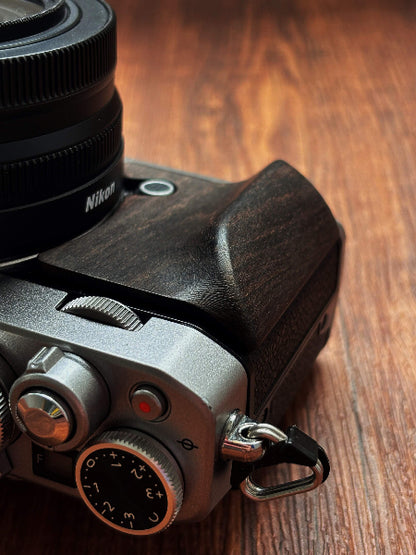 Nikon zfc camera with a black wood grip on a wooden surface