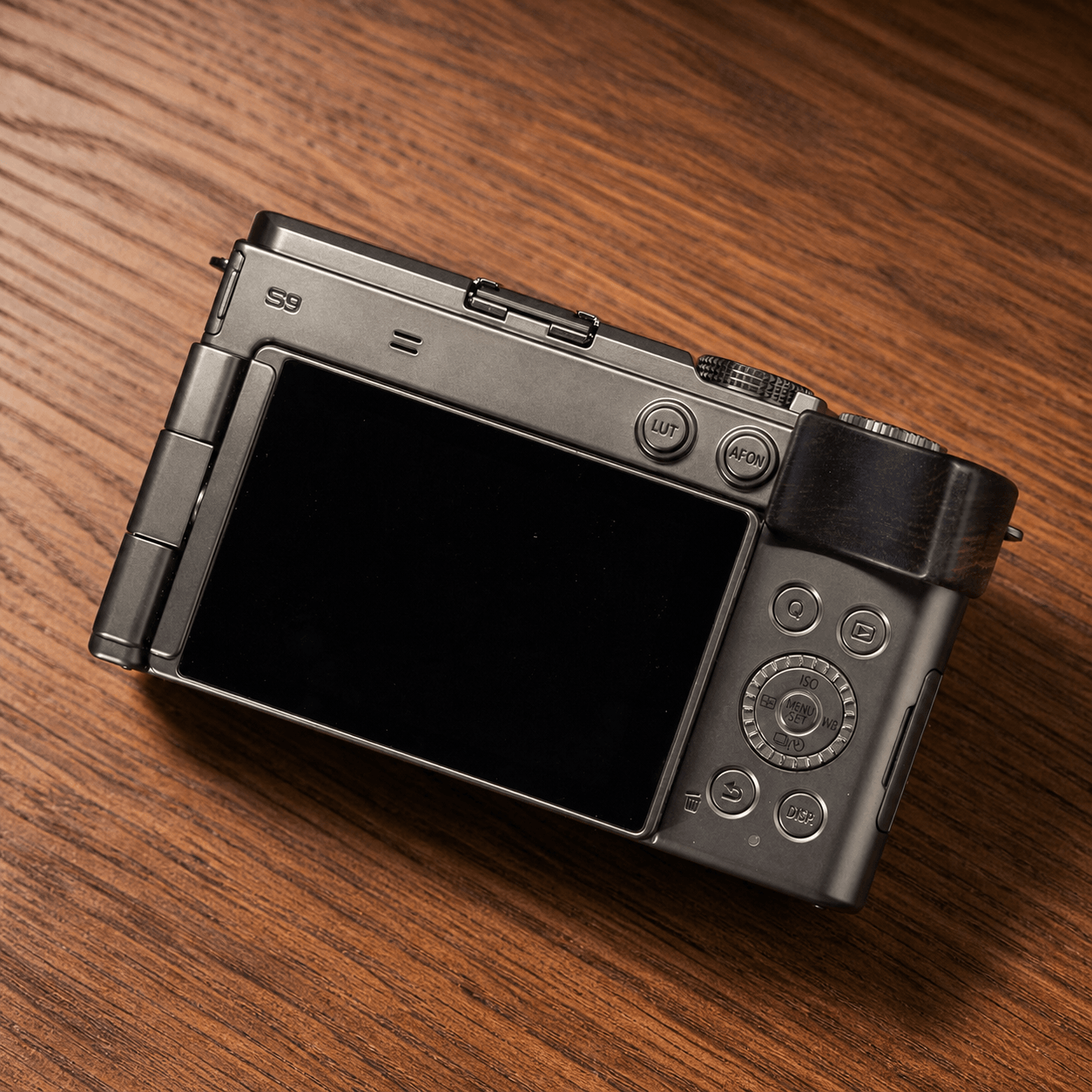 A Panasonic S9 camera with a black wood grip on white background