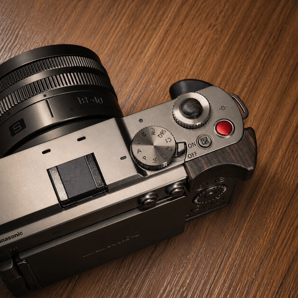 Close-up of a Panasonic S9 camera body with a silver and dark gray top plate, featuring a wood finger grip.