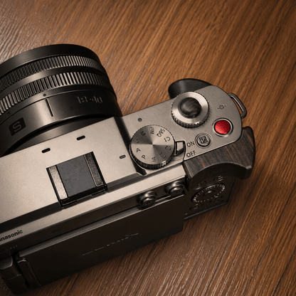 Close-up of a Panasonic S9 camera body with a silver and dark gray top plate, featuring a wood finger grip.