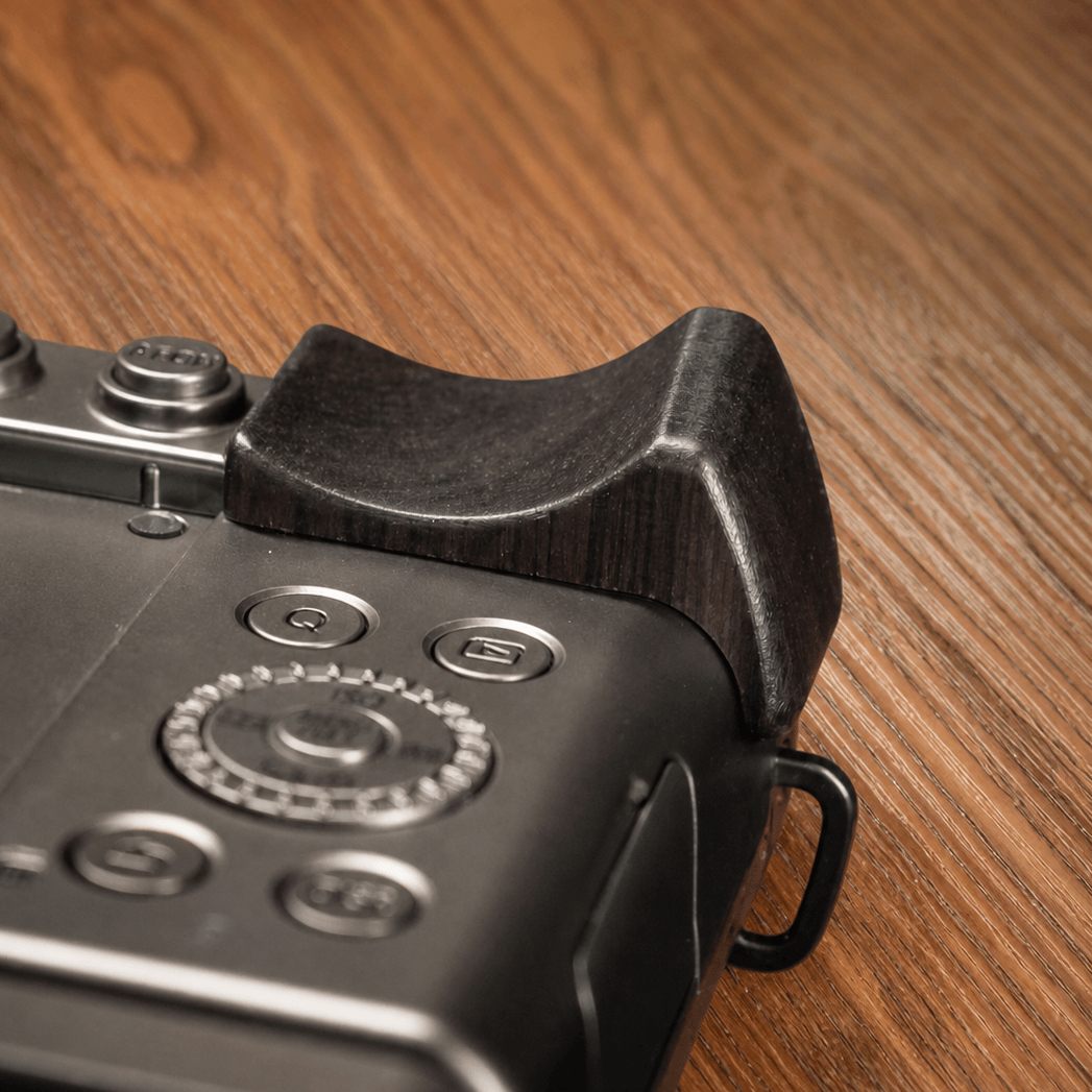 Close-up of a Panasonic S9 body with a dark brown wooden grip attachment on the top right.