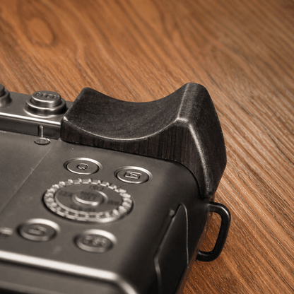 Close-up of a Panasonic S9 body with a dark brown wooden grip attachment on the top right.