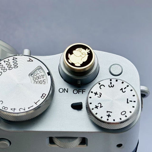 Close-up of a camera shutter release button with Pokémon Psyduck engraved