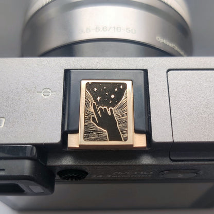 Gold brass hot shoe cover with engraved hand and stars design on Fujifilm X100