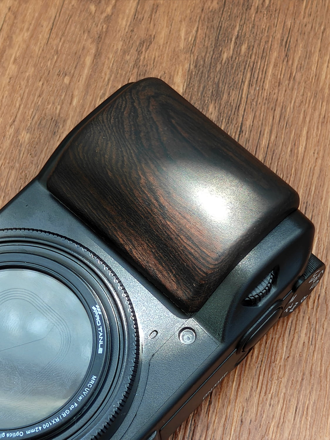 Ricoh GR III camera with handcrafted wooden grip on wooden desk - front angle