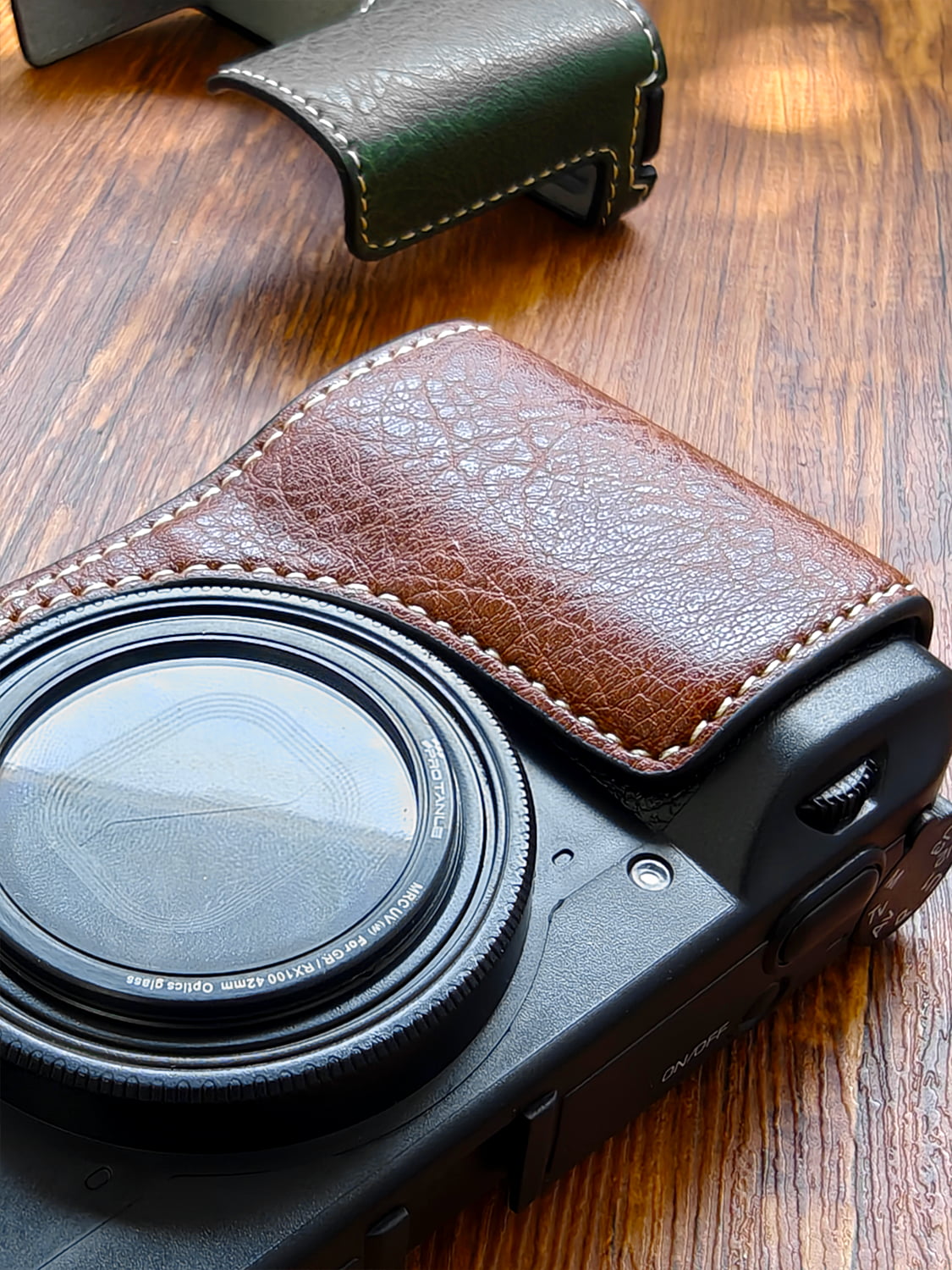 Ricoh GR3 camera with a brown leather case on a wooden surface