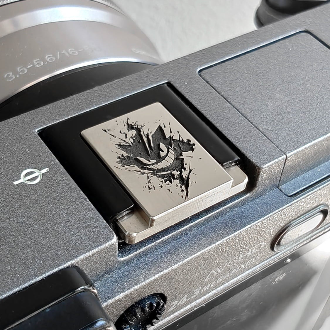 Close-up of a silver Pokémon Gengar engraved hot shoe cover on mirrorleass camera