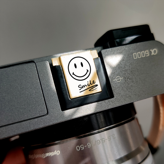 Camera with a smiley face sticker labeled 'Smile' on a gray background