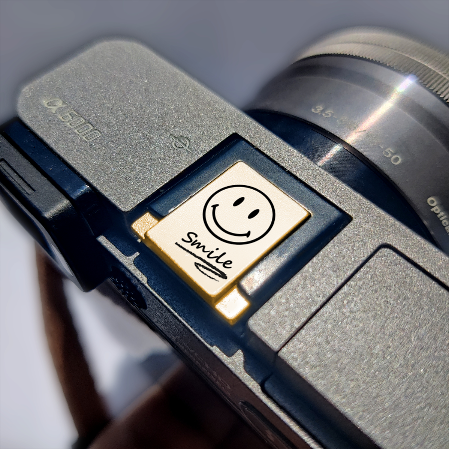 a smiley face hot shoe cover labeled 'smile' on sony camera