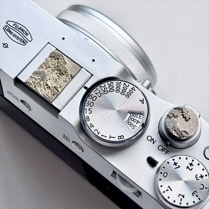 Close-up of a brass sea wave hot shoe cover and shutter release on fujifilm X100vi camera