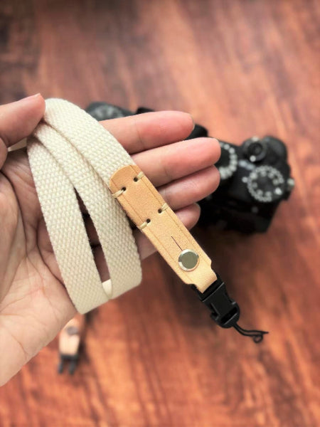 Close-up white canvas top leather camera strap on hand