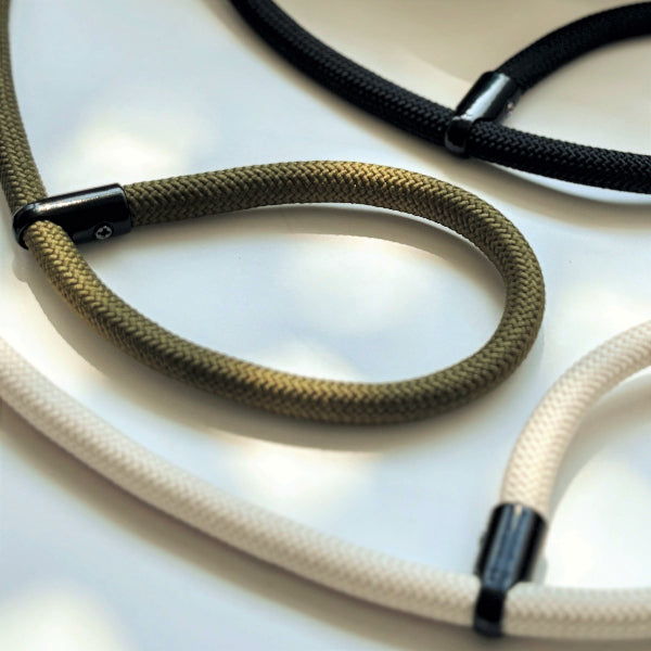 Close-up of three colors camera rope with black metal clasps on a light background