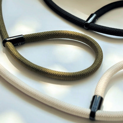 Close-up of three colors camera rope with black metal clasps on a light background